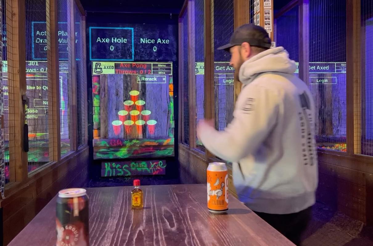 man playing axe pong at an axe throwing bar